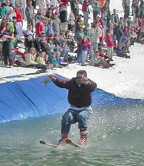 Skier skims pond at annual pond skimming contest at Burke Mountain in Northern Vermont